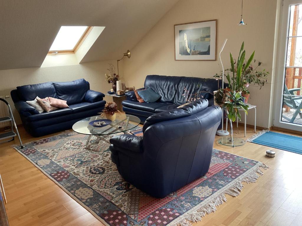 a living room with black leather couches and a rug at Im schönen Garten in Haldensleben