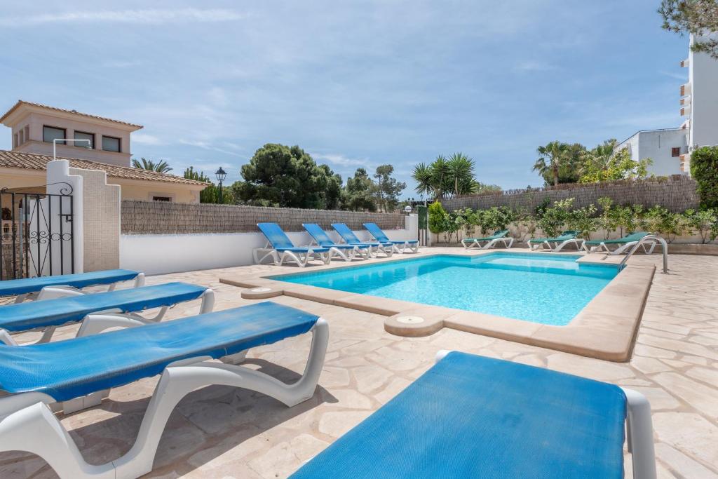 a swimming pool with blue lounge chairs and a swimming pool at Apartamentos Karin 1ºa in Cala d´Or