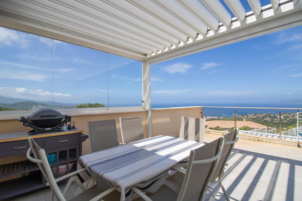 a table and chairs on a balcony with a view of the ocean at Sublime Appart Neuf in Albitreccia