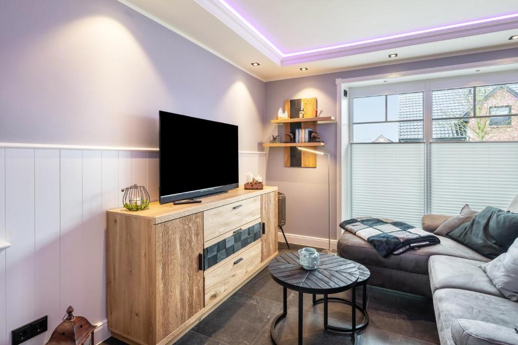 a living room with a flat screen tv on a wooden entertainment center at Kleine Auszeit in Dagebüll