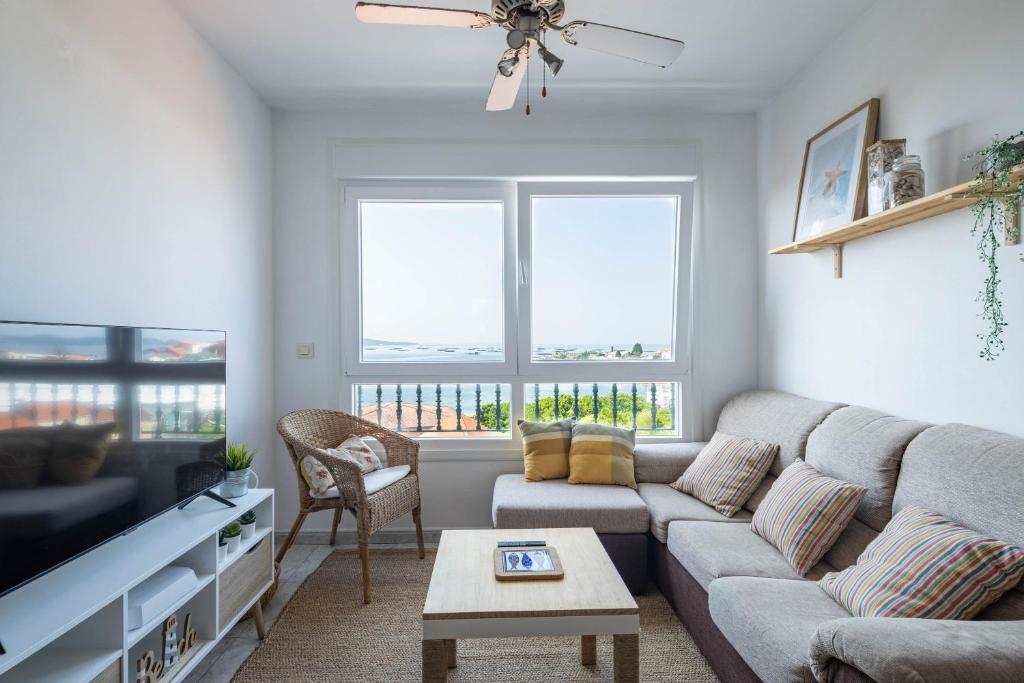 a living room with a couch and a tv at Primera línea de playa Cabo Cruz in Boiro