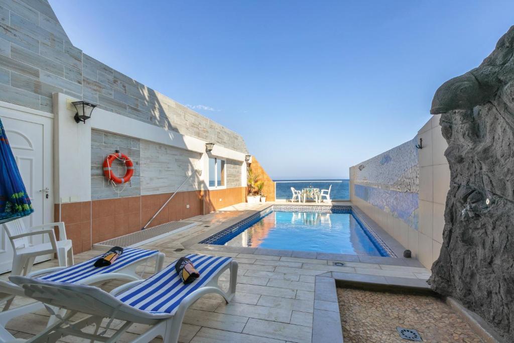 a swimming pool with two chairs next to a building at Seaside House With Heated Pool in Pájara