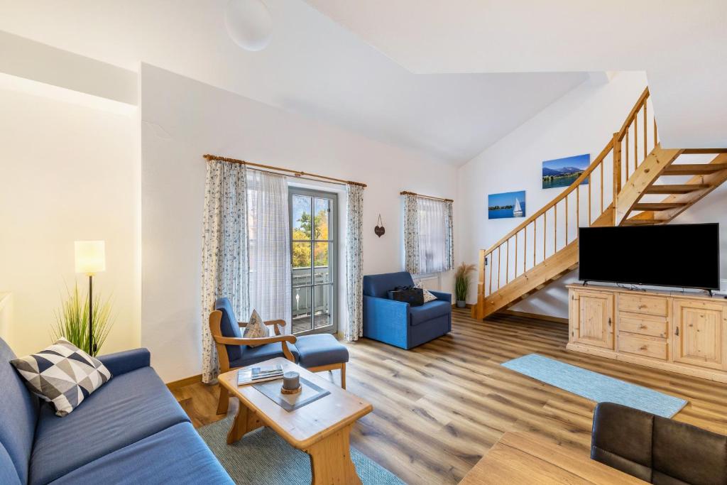 a living room with a blue couch and a tv at Fewo Brünnstein - Zimmer 50 in Oberaudorf
