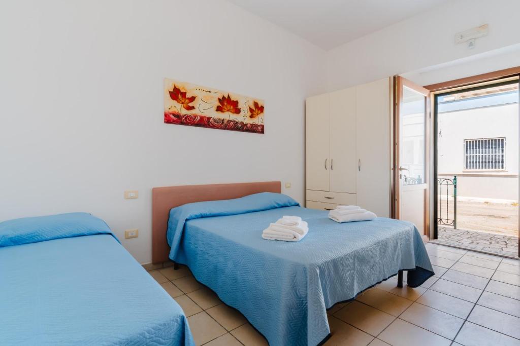 a bedroom with two beds with blue sheets at La casetta 461 in Torre San Giovanni Ugento