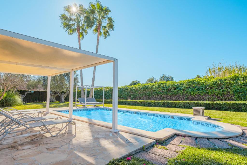a swimming pool with a gazebo and palm trees at Es Rafal in Santa Margalida