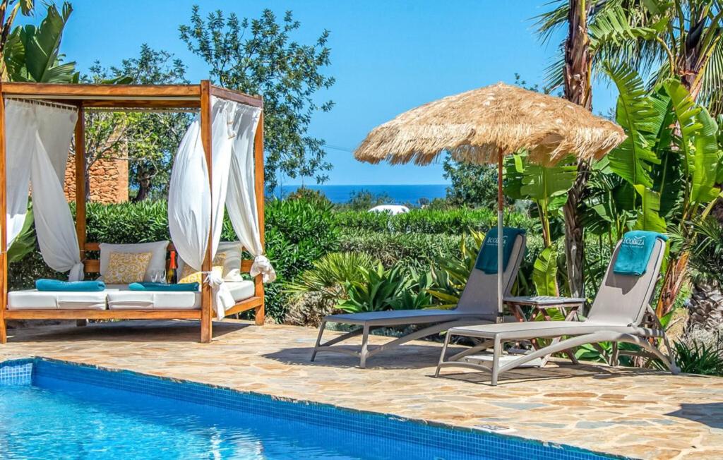 a resort pool with two chairs and an umbrella at Can Andreuet in Sant Carles de Peralta
