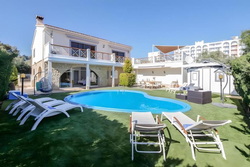 a villa with a swimming pool and lounge chairs at Tres Palmeras in Calas de Mallorca