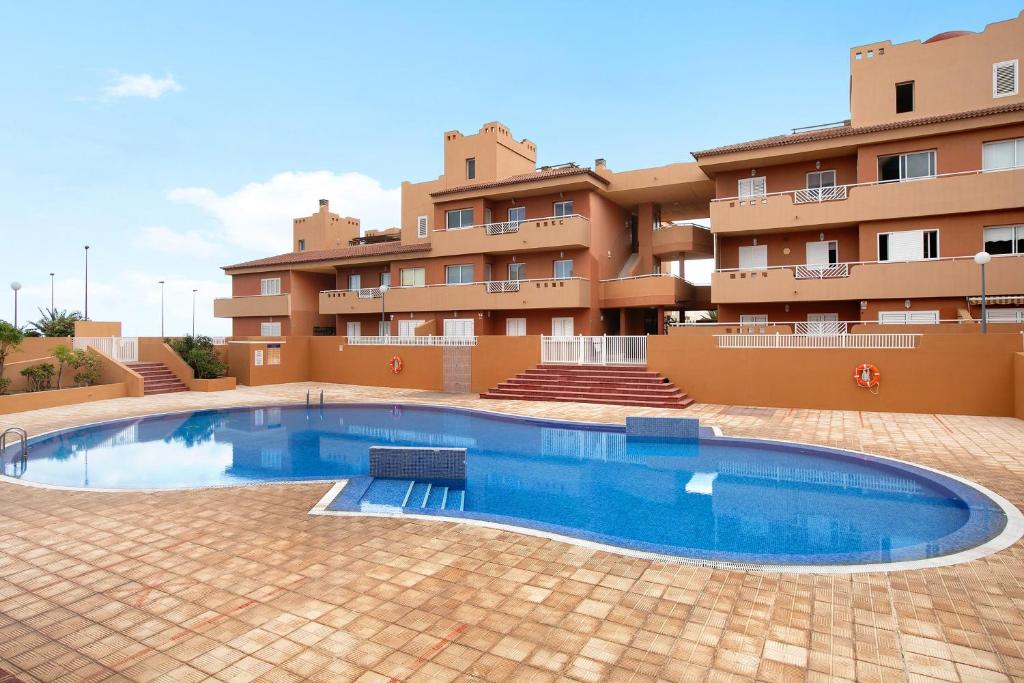 a swimming pool in front of a building at Beach Front Apartment Puertito in Puertito de Güímar