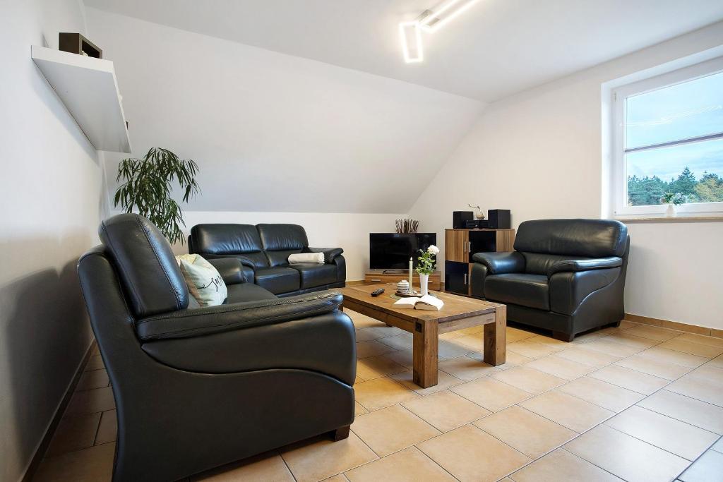 a living room with two leather chairs and a table at Ferienwohnung Bella in Fuhlendorf