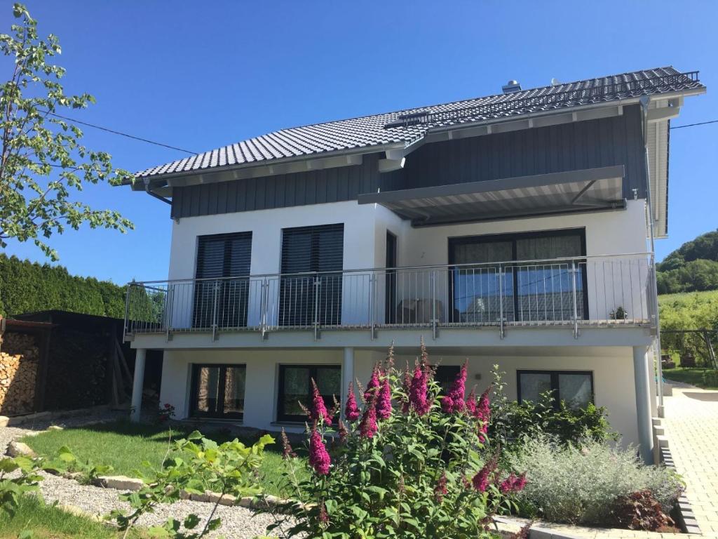 a house with a balcony and purple flowers at Ferienwohnung Gluiber in Beuren