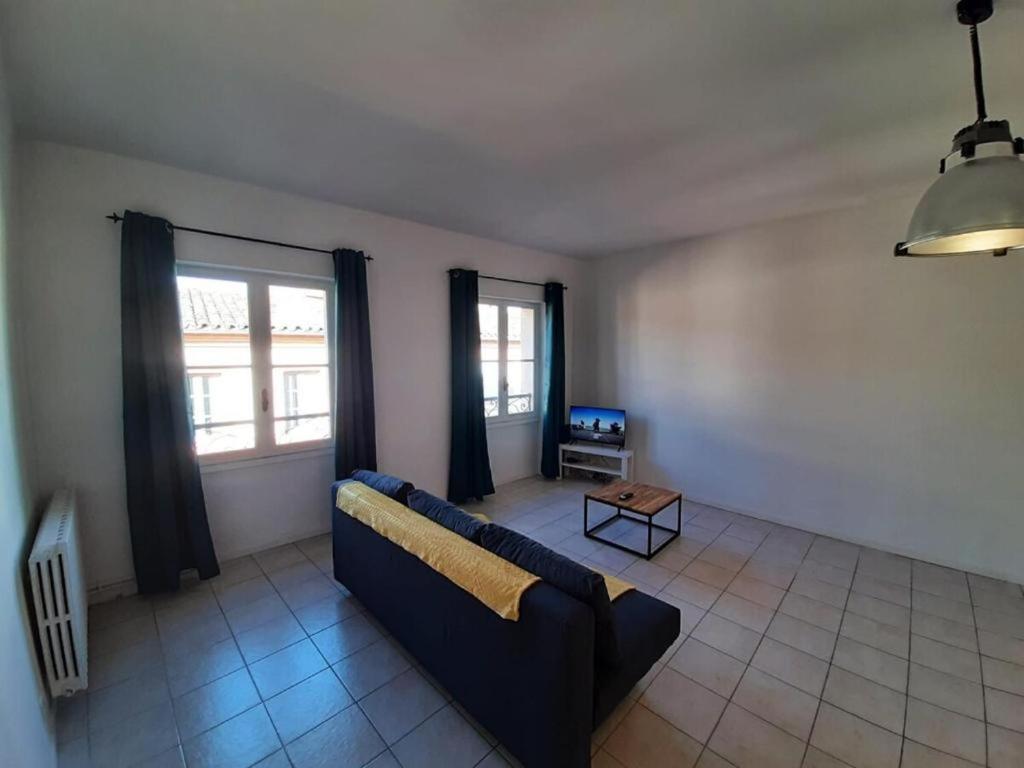 a living room with a couch and a tv at Le beau 25 République in Montauban