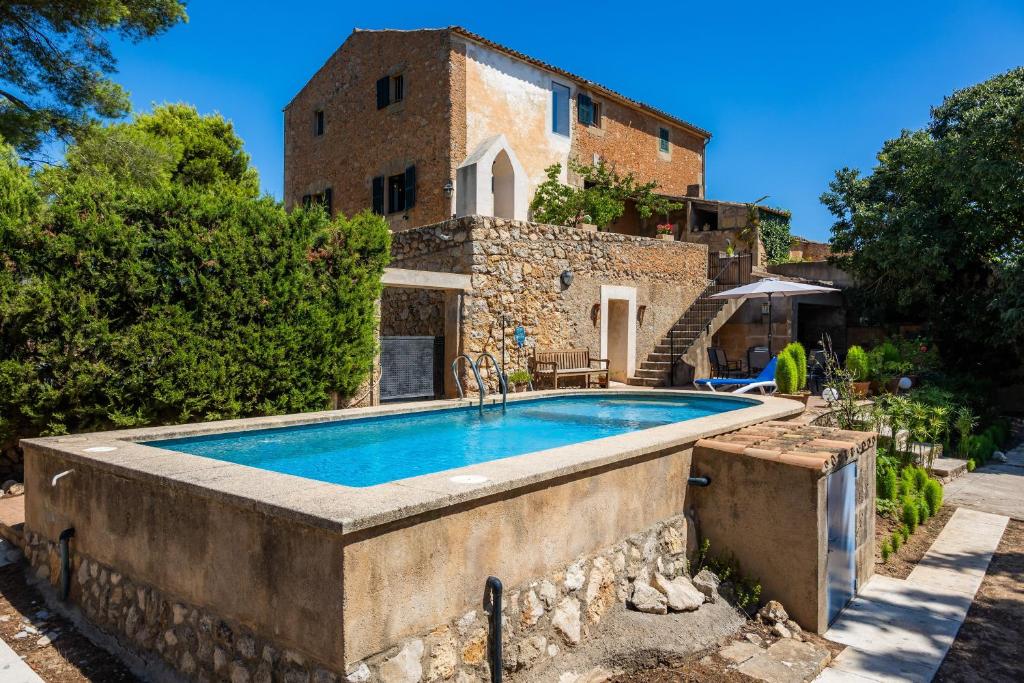 an outdoor swimming pool in front of a house at Finca So na Sopa in Artá