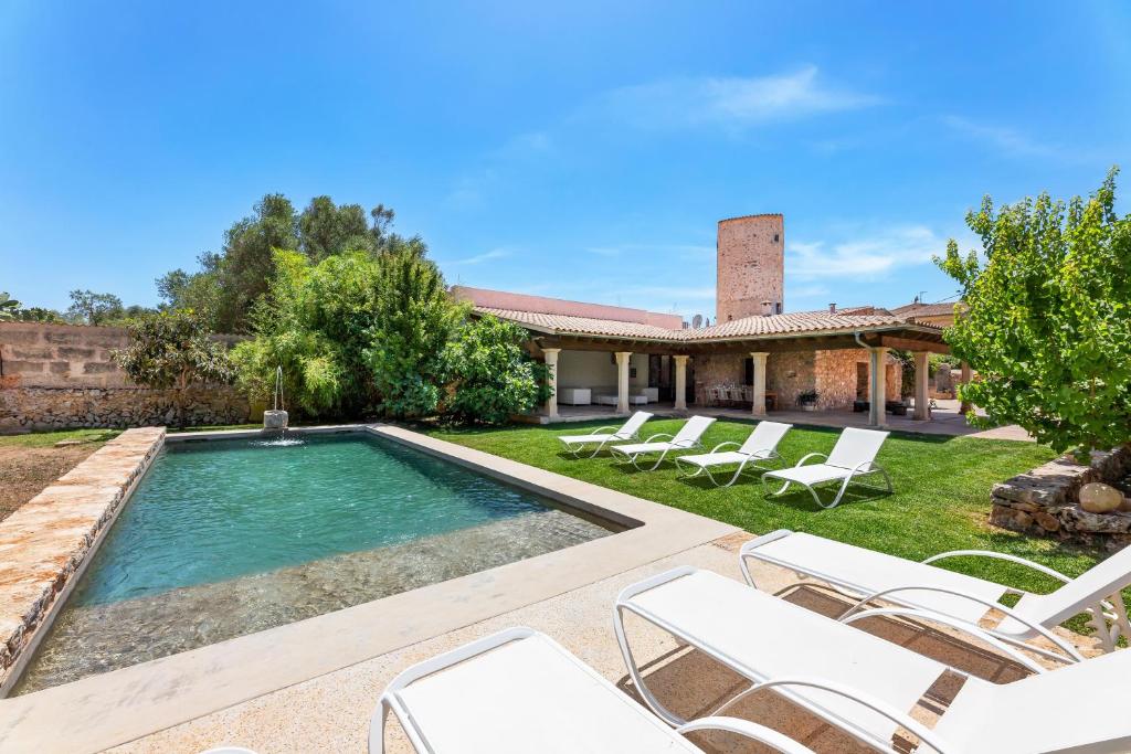 a swimming pool with chairs and a house at Can Estela in Sencelles