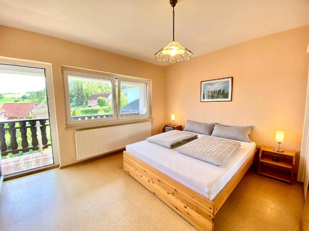 a bedroom with a bed and two windows at Ferienwohnung Alraftsblick in Waldeck