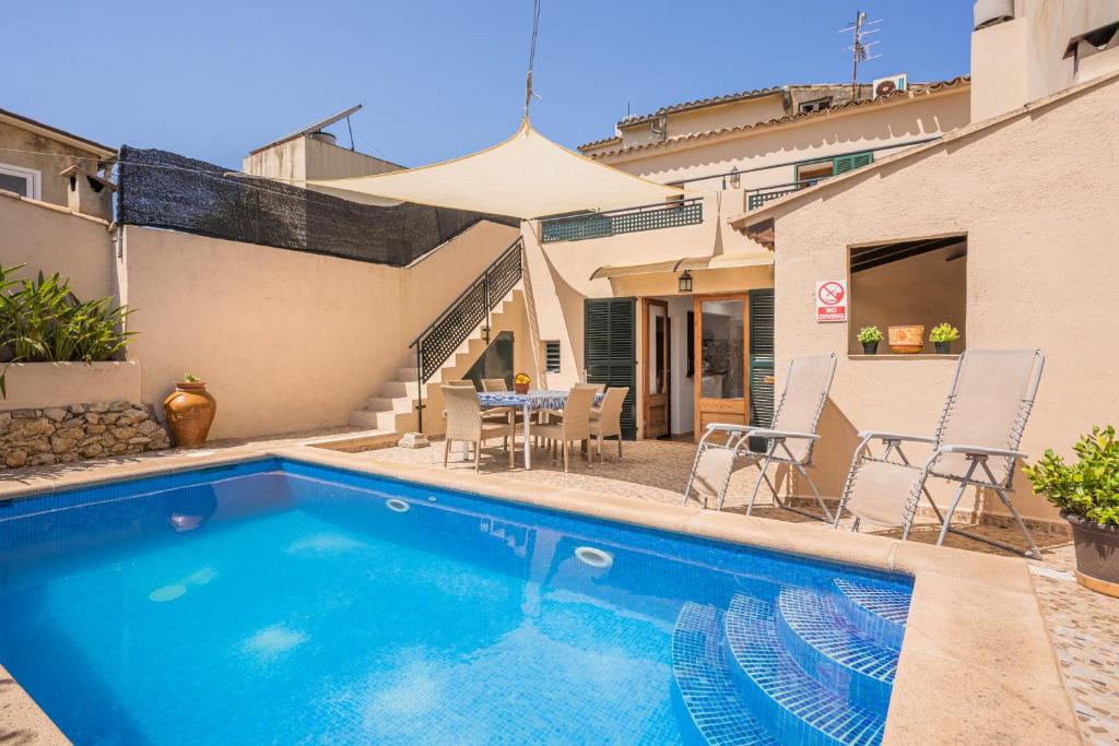 a swimming pool with chairs and an umbrella next to a house at Ca la Pradina in Pollença