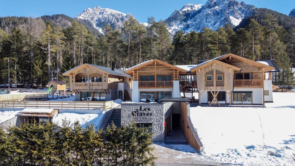 a house in the snow with mountains in the background at Les Ciases Chalets Dolomites Apt 4 in San Vigilio Di Marebbe