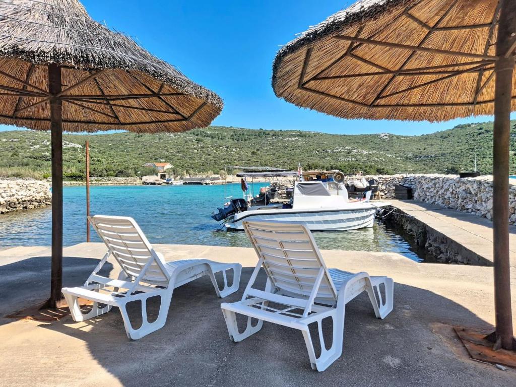 two chairs and an umbrella on a beach with a boat at Holiday Home Marica by Interhome in Tkon