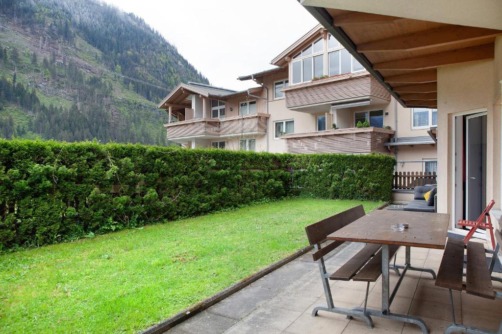 a patio with a wooden table and a green yard at Apartment Tux in Mayrhofen