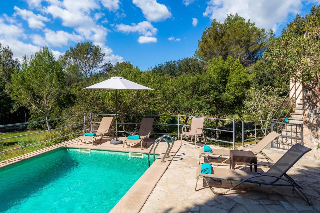 a swimming pool with chairs and an umbrella at Can Company in Campanet