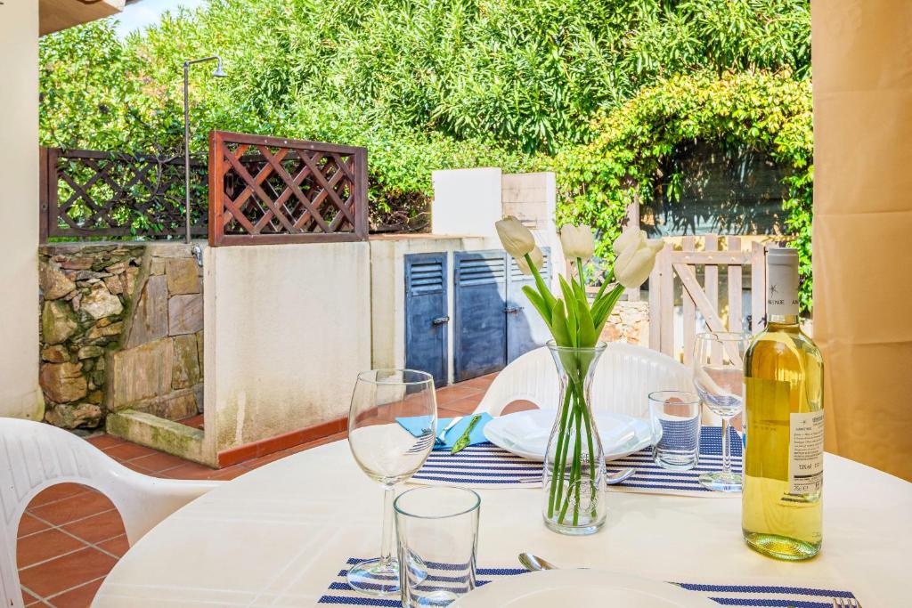 a table with a bottle of wine and a vase with flowers at Residence Asfodeli E4 in San Teodoro