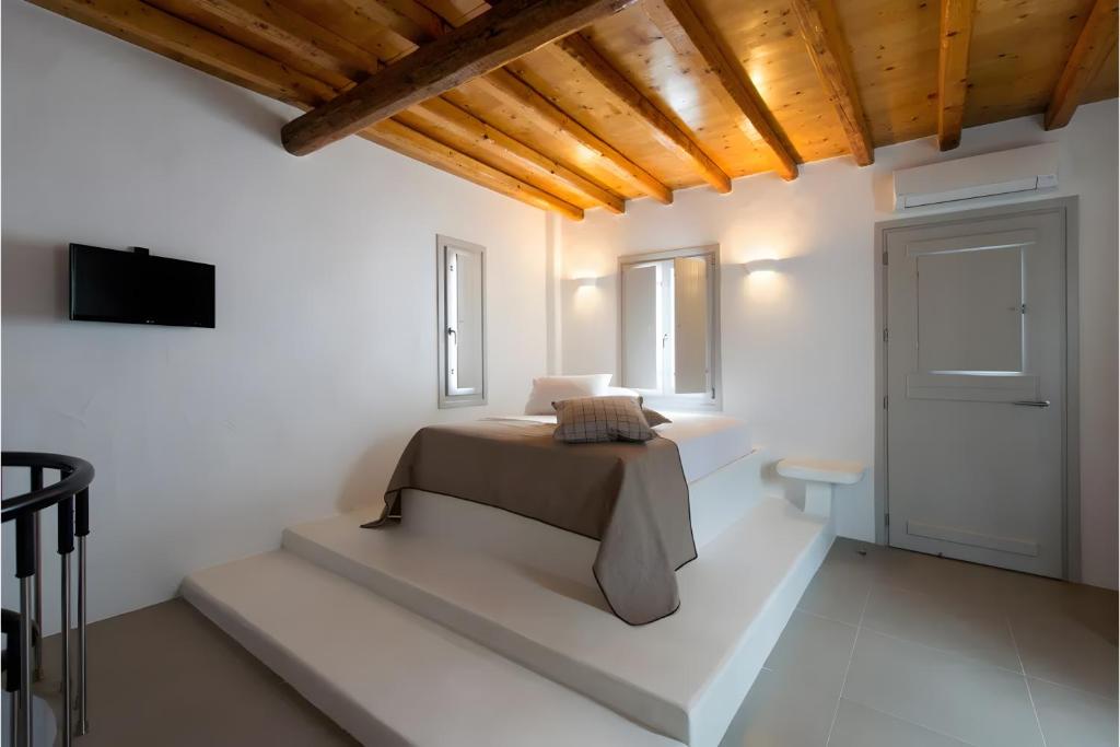 a bedroom with a bed and a tv on a wall at Echinousa Kimolos Maisonette no4 in Kimolos