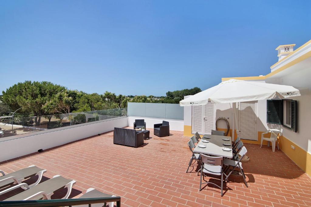 a patio with tables and chairs and an umbrella at Quinta Alegre Tavira T3 in Luz de Tavira