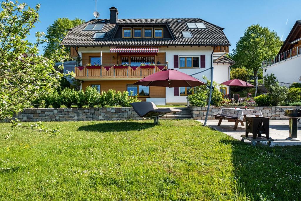 a house with an umbrella and a chair in the yard at Haus Leufke in Lenzkirch
