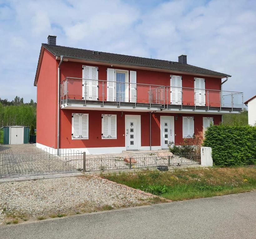a red house with white windows and a balcony at Ferienhaus Emelie Geiseltalsee in Mücheln