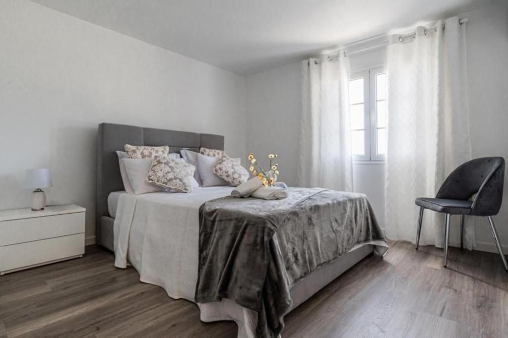 a white bedroom with a bed and a chair at Sweet Home Madeira in Camacha