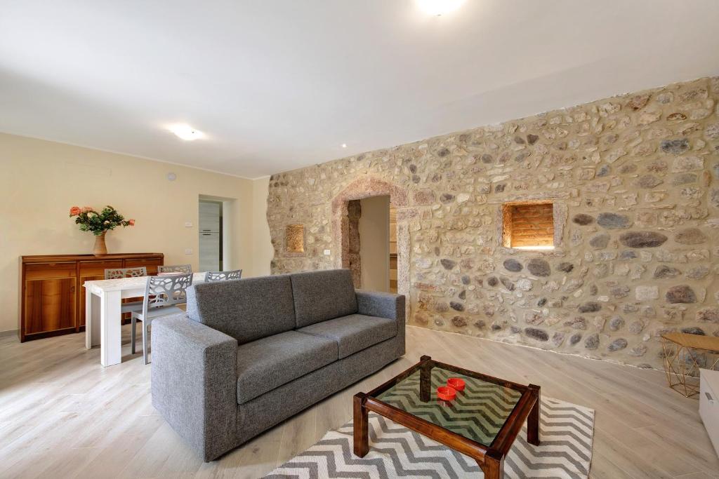 a living room with a couch and a stone wall at Casa Vera Aurora Lake Garda in Torri del Benaco