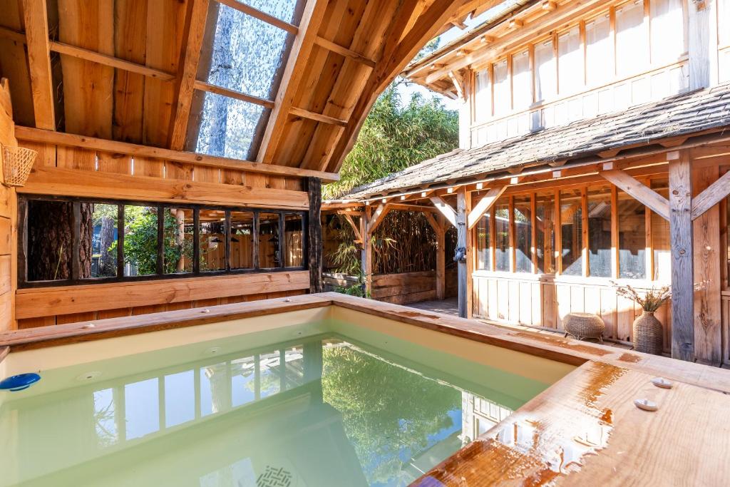 an indoor swimming pool in a wooden house with a building at Villa Bayani Été in Lacanau