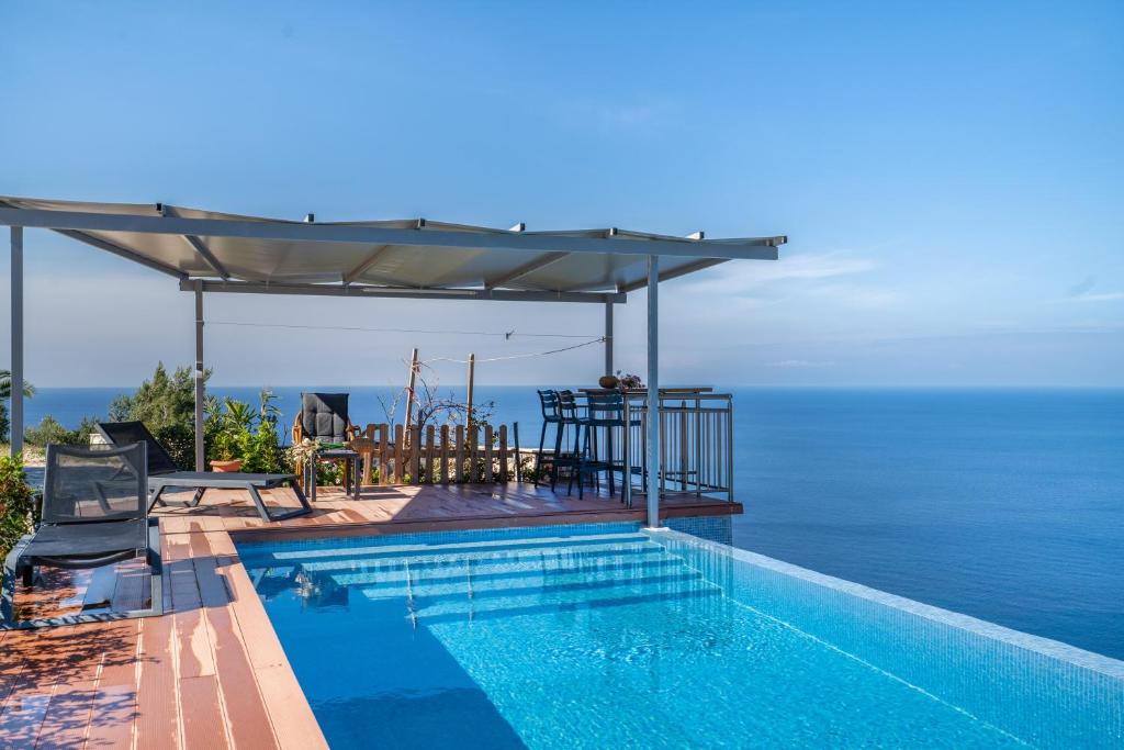 a swimming pool with an umbrella and the ocean at Villa sea view 1 in Athani