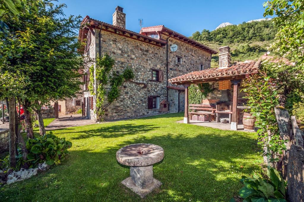 a garden with a stone bench in front of a building at El Serenal in Santa Maria de Valdeón