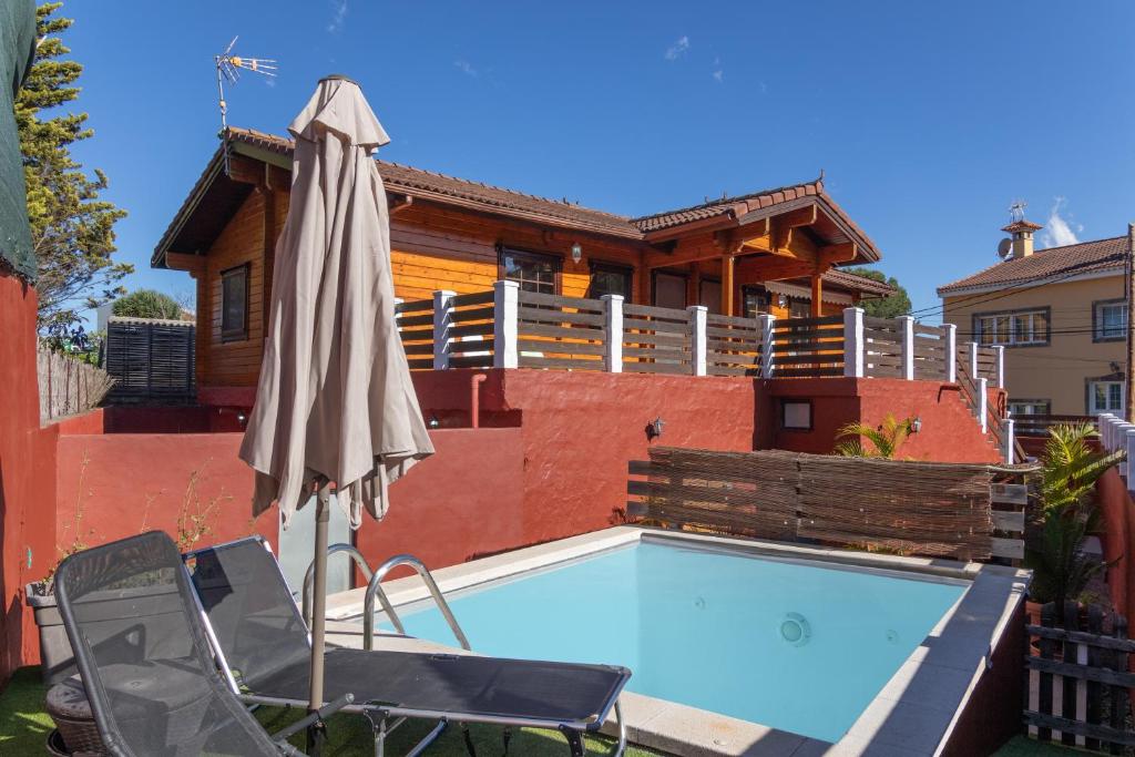 a pool with two chairs and an umbrella and a house at Villa Tanqueta in Santa Brígida