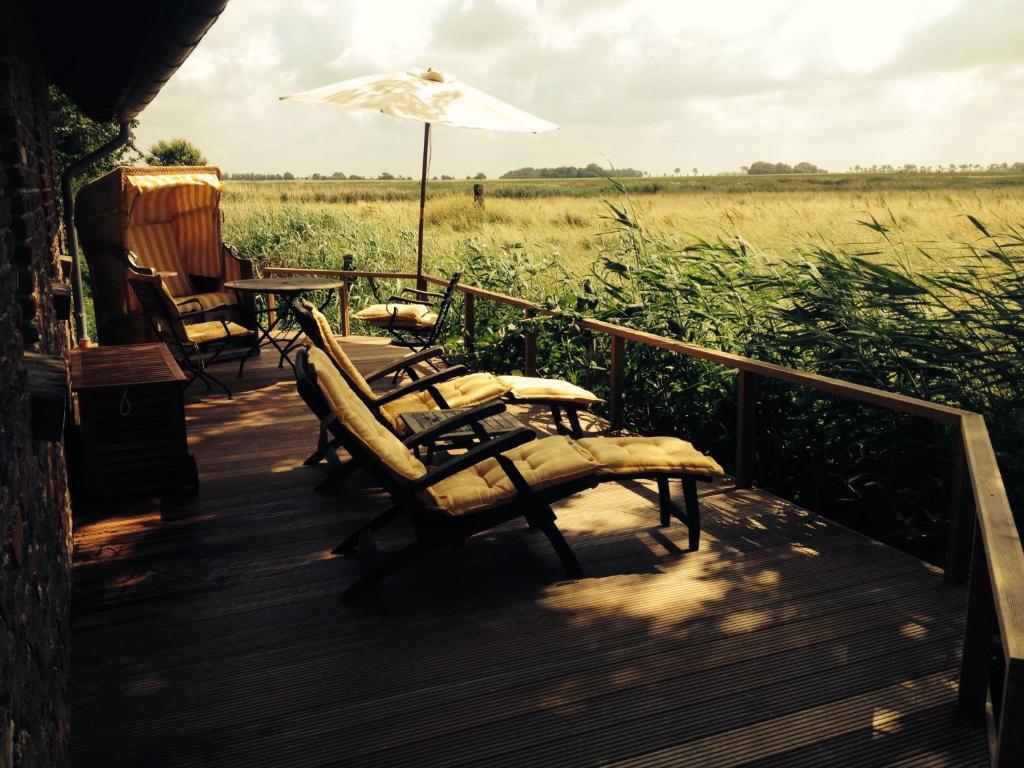 a porch with chairs and a table and an umbrella at Feriencottage Nordseeluft in Siekbüll