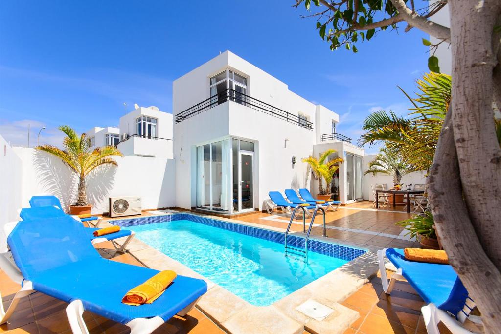 a villa with a swimming pool and blue chairs at Luis ii in Puerto del Carmen