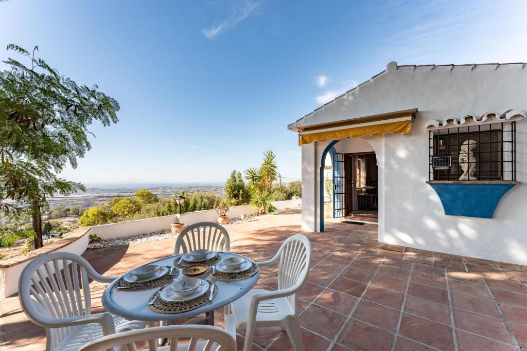 a patio with a table and chairs and a house at Mijas la Nueva in Mijas