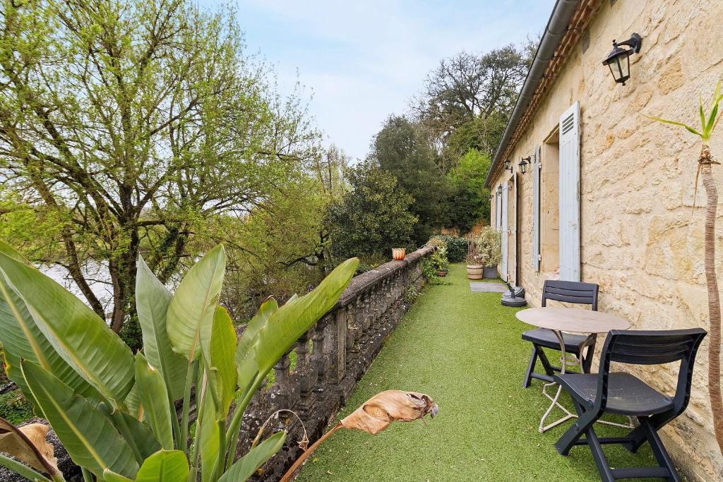 a dog laying on the grass next to a table and chairs at La Belle Gabarre in Groléjac