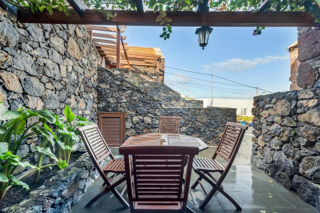 a table and chairs on a patio with a stone wall at El Almendro in Tesbabo