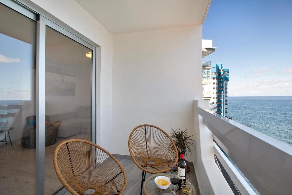 a balcony with two chairs and a table with a view of the ocean at Salitre Suites Tamara in Tacoronte