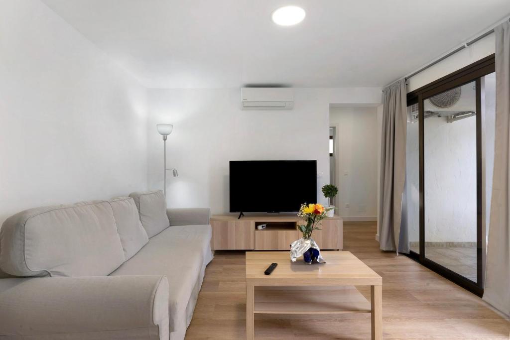 a living room with a couch and a tv at Suite Deluxe Puerto Rico 11 in Puerto Rico de Gran Canaria
