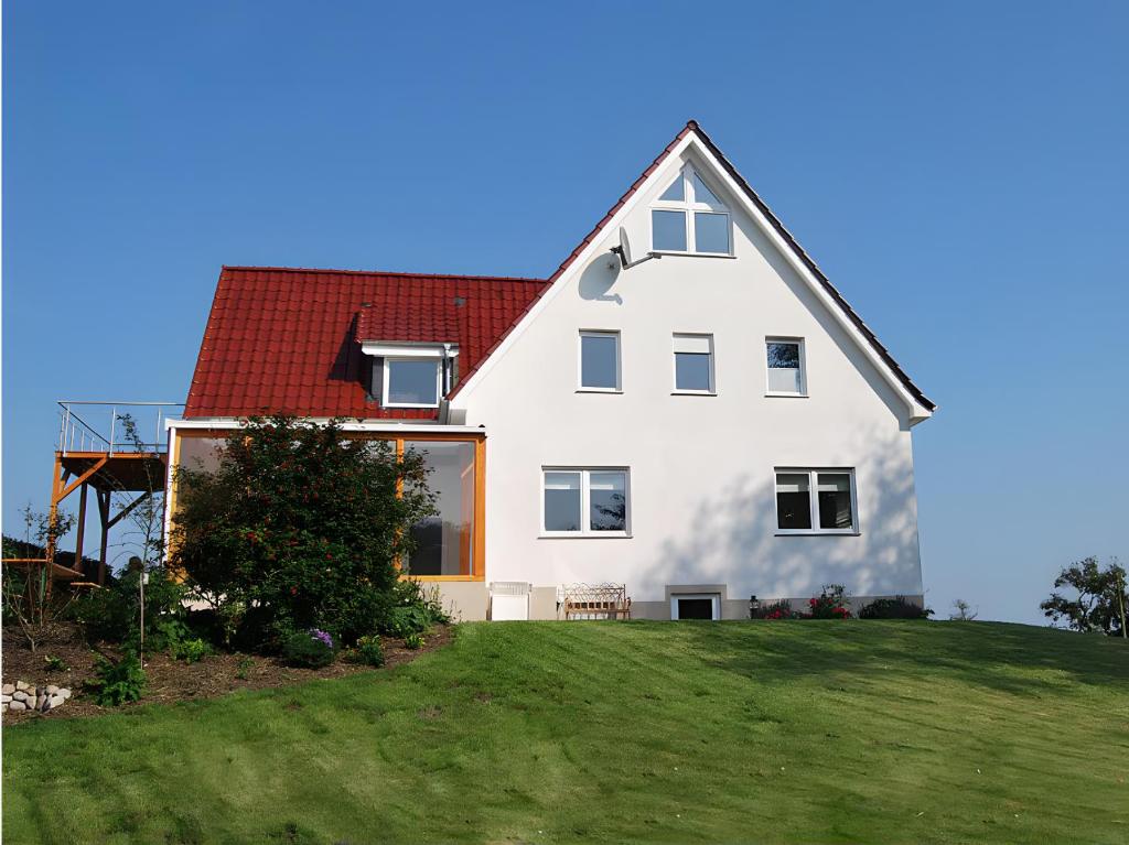 a white house with a red roof on a hill at Ferienhaus Kuhweid in Drochtersen