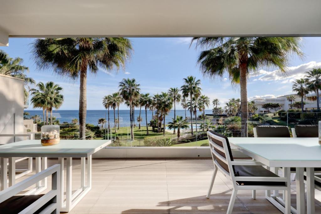 a dining room with palm trees and a view of the ocean at Modern frontline beach - Estepona in Estepona