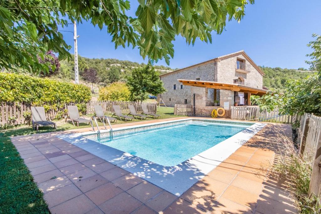 a swimming pool in a yard with chairs and a house at El Puig De Fonollet in Puigreig