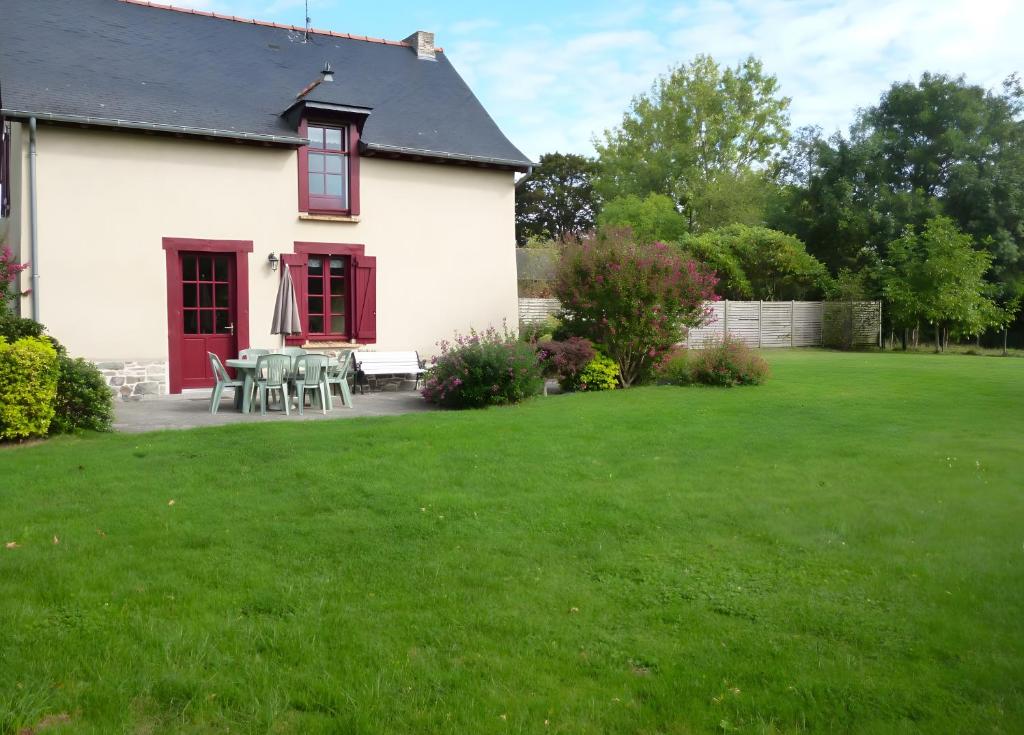 a white house with a table and chairs in a yard at Gîte Le Guerichet in Betton