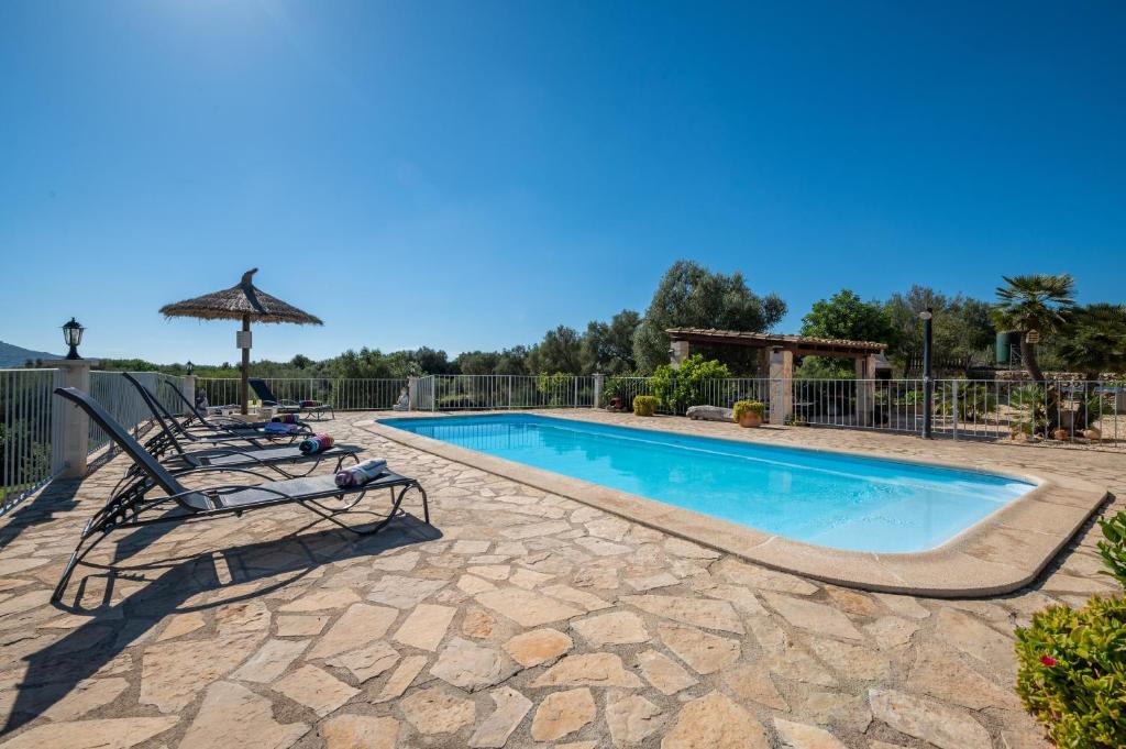 a swimming pool with two lounge chairs and an umbrella at Finca Son Puca in Petra