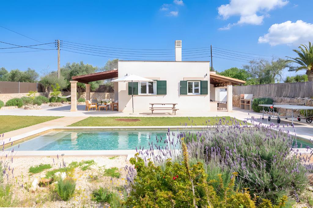 a house with a pool in front of a yard at Las Estrellas Cala Llombards in Cala Llombards