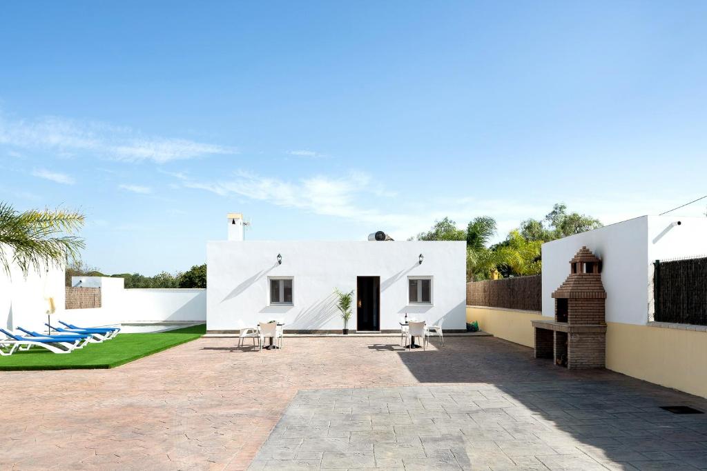 a white house with a patio and a yard at Villa Montenmedio - Carmelo in El Soto