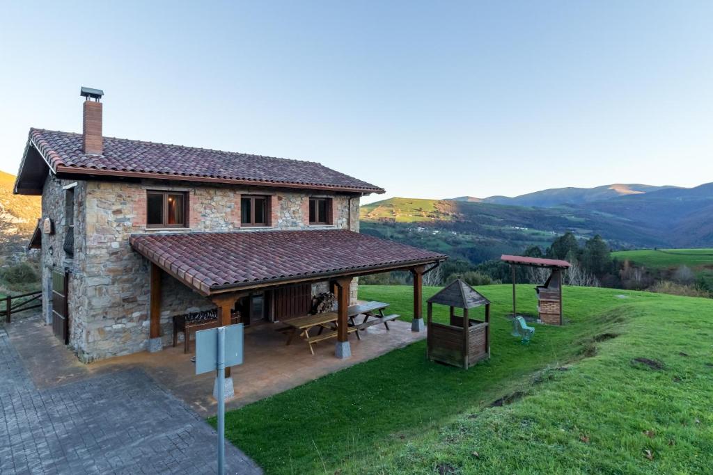a stone house with a picnic table in a field at El Paraiso del Yayo in Ramales de la Victoria