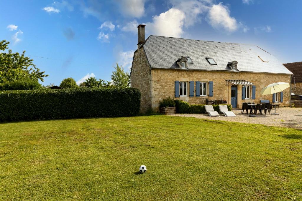 a dog laying in the grass in front of a house at Gite La Mauratie -4 chambres in Jayac